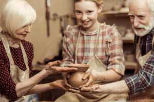 Grandmother and grandfather with granddaughter making pottery at workshop