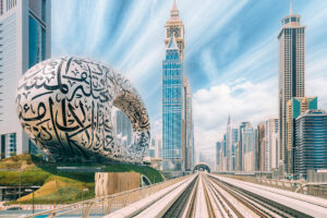 Metro railway among among glass skyscrapers in Dubai. Traffic on street in Dubai. Museum of the Future in Dubai. Cityscape skyline. Urban background.